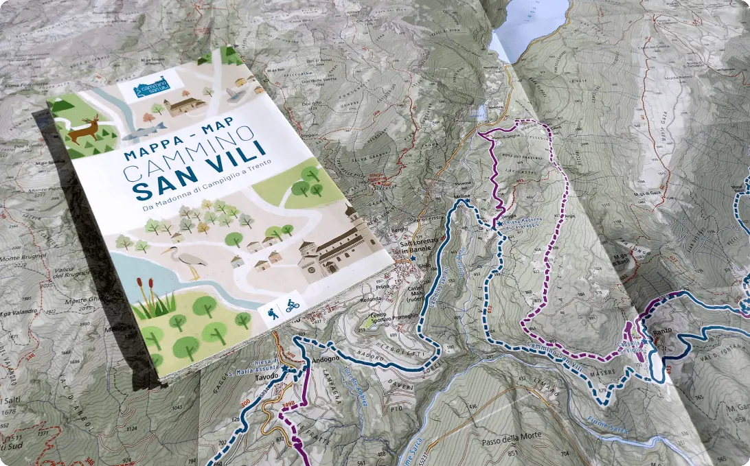 Mappa cartacea stampata di un cammino appoggiata su una carta topografica